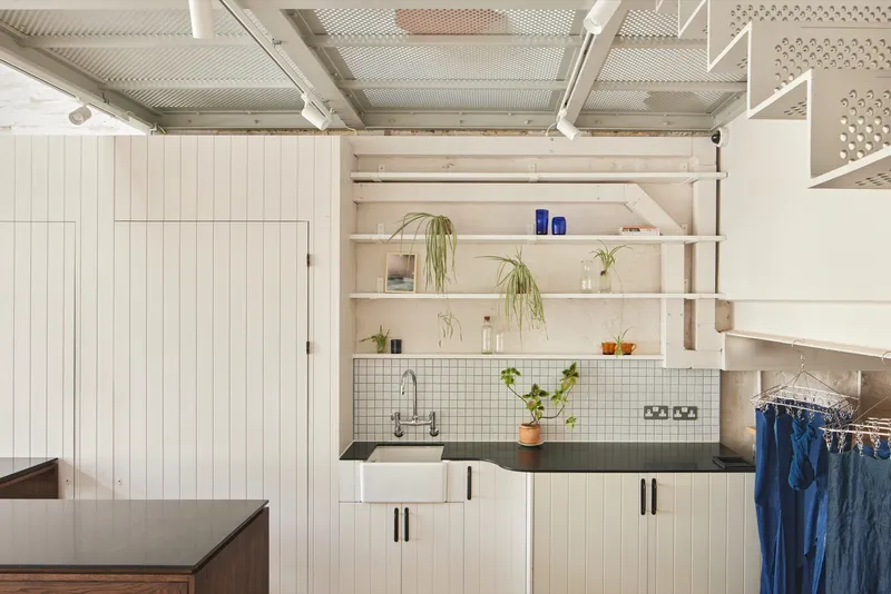 Kitchen counter with white tile backsplash and open timber shelves holding potted plants