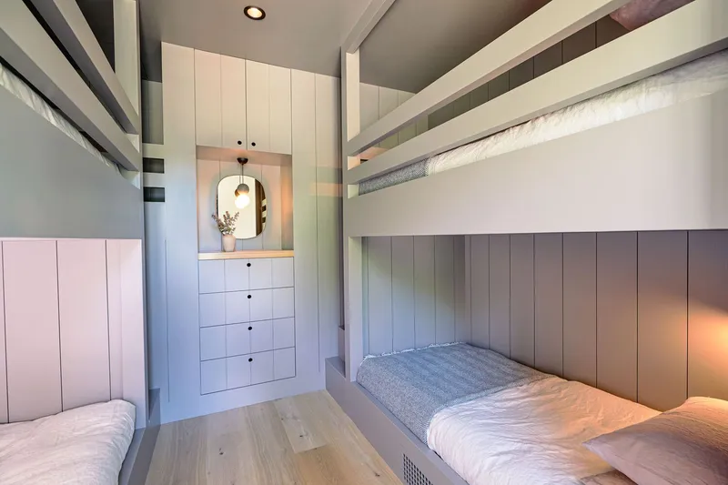 Built-in bunk beds with vertical paneling and integrated storage drawers beneath a lofted ceiling