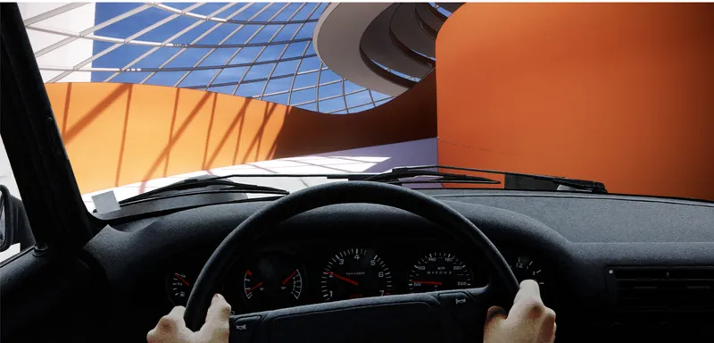 View through a car windshield of the spiraling interior ramp and orange wall panels beneath blue sky