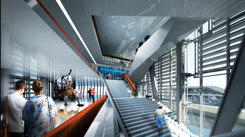 Interior atrium with wide stairs, orange handrails, skylight above, and visitors on multiple levels