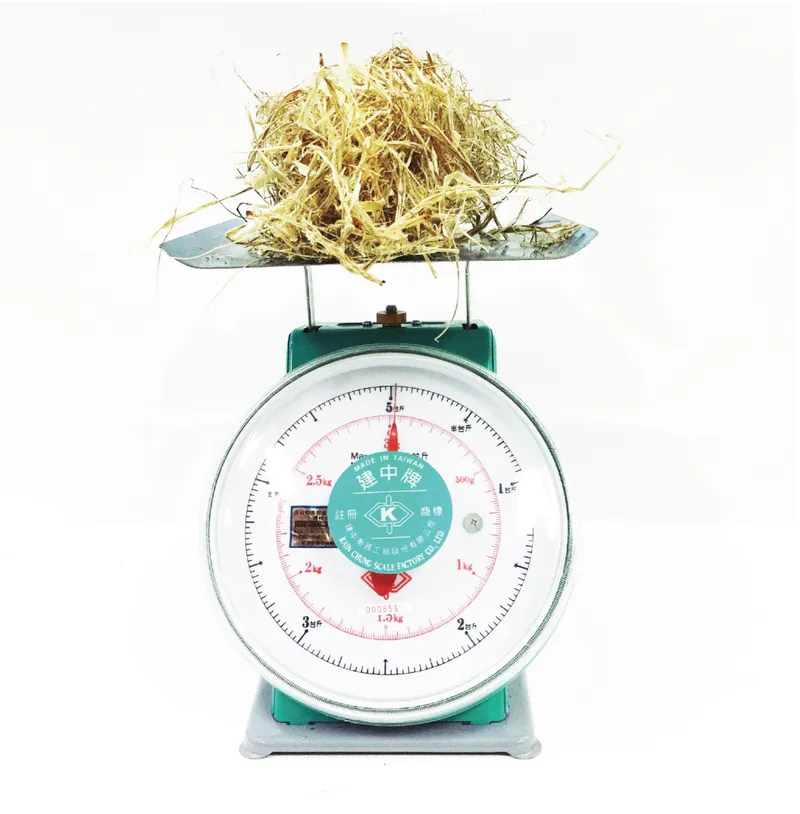 Vintage teal kitchen scale with a mound of dried straw placed on the weighing platform