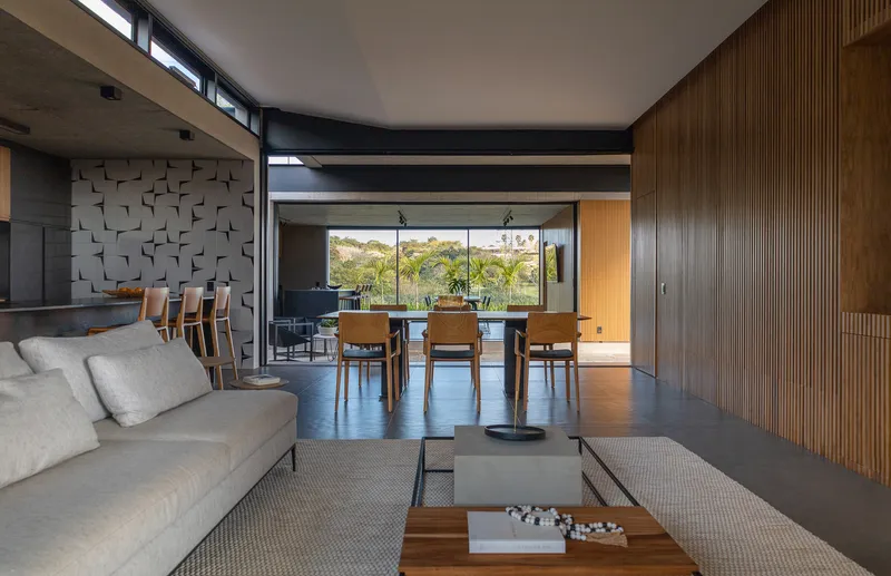 Open-plan living and dining area with vertical wood paneling, textured wall tiles, and clerestory windows