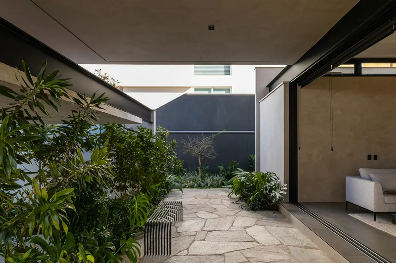 Interior courtyard with irregular stone paving, planted beds, and dark rendered walls under an open sky