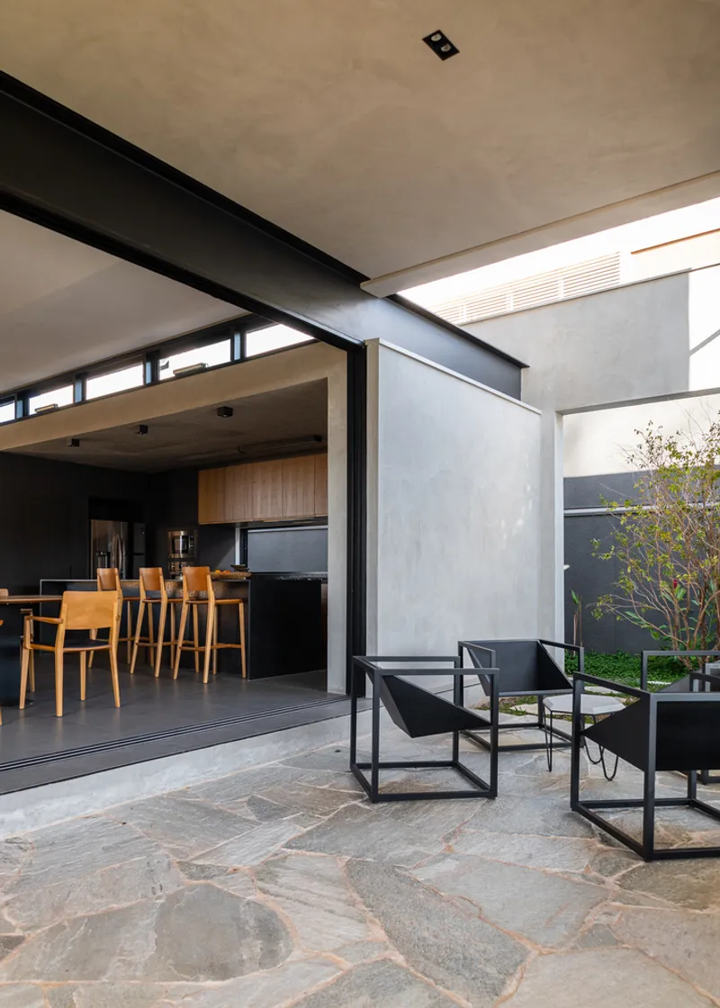 Covered terrace with stone floor, steel frame seating, and views into the kitchen and courtyard