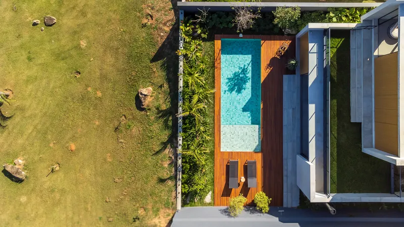 Aerial view of the swimming pool with timber deck adjacent to flat roof volumes and lawn
