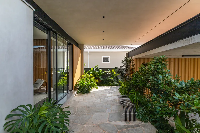 Internal courtyard with stone paving, planted beds of tropical foliage, and sliding glass walls