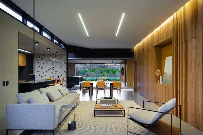 Open-plan living area with ribbed timber wall, linear ceiling lights, and view through to dining space