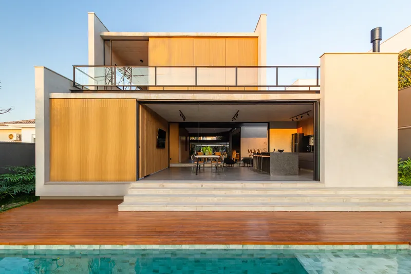 Rear elevation with timber-clad volume, cantilevered balcony, timber deck, and swimming pool in foreground