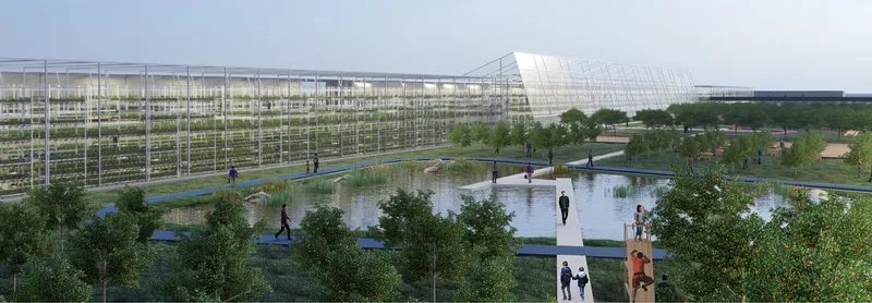 Long glazed greenhouse structure with angled roof element overlooking a landscaped water feature and walking paths