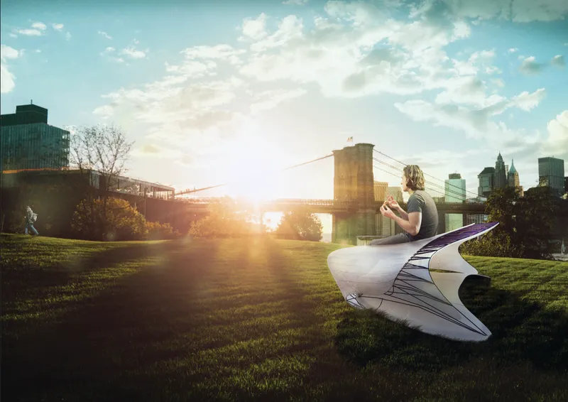 Curved seating installation on a grass lawn at sunset with a bridge visible in the background