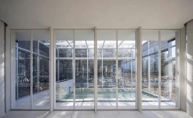 Floor-to-ceiling sliding glass doors opening to a courtyard pool with metal screening and walkways