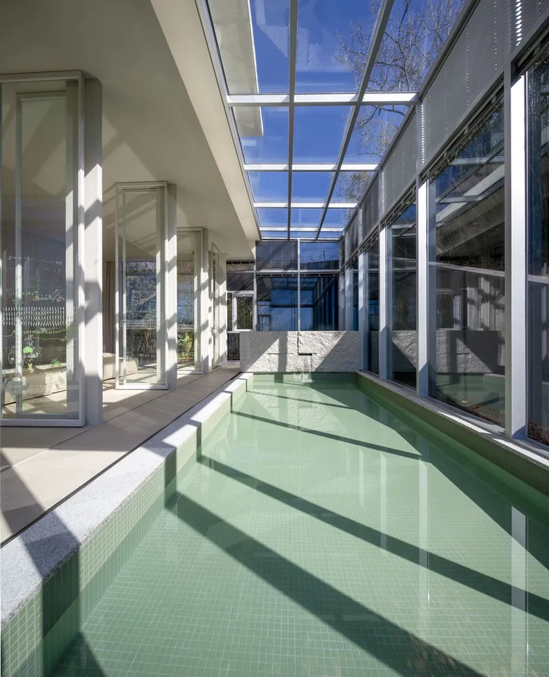 Interior courtyard pool with pale green mosaic tile and glass skylight filtering midday sun
