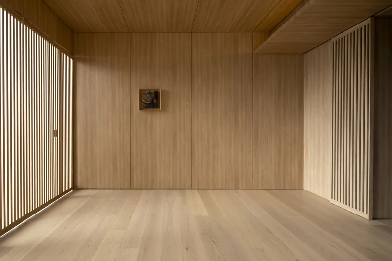 Wood-paneled room with vertical slatted screens flanking walls and ceiling in warm light