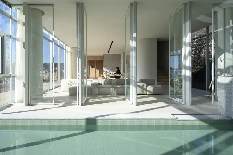 View through open folding glass doors to living space beyond the pool terrace