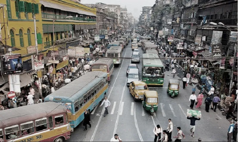 Elevated view of a congested roadway filled with buses, taxis, and pedestrians crossing between lanes