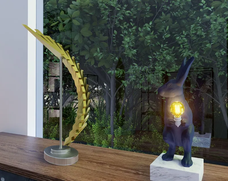 Yellow wing sculpture on a timber deck at dusk with garden foliage in the background