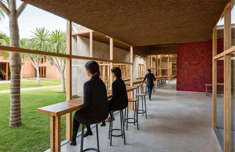 Covered bar area with timber framing and woven ceiling opening to a courtyard with palm trees