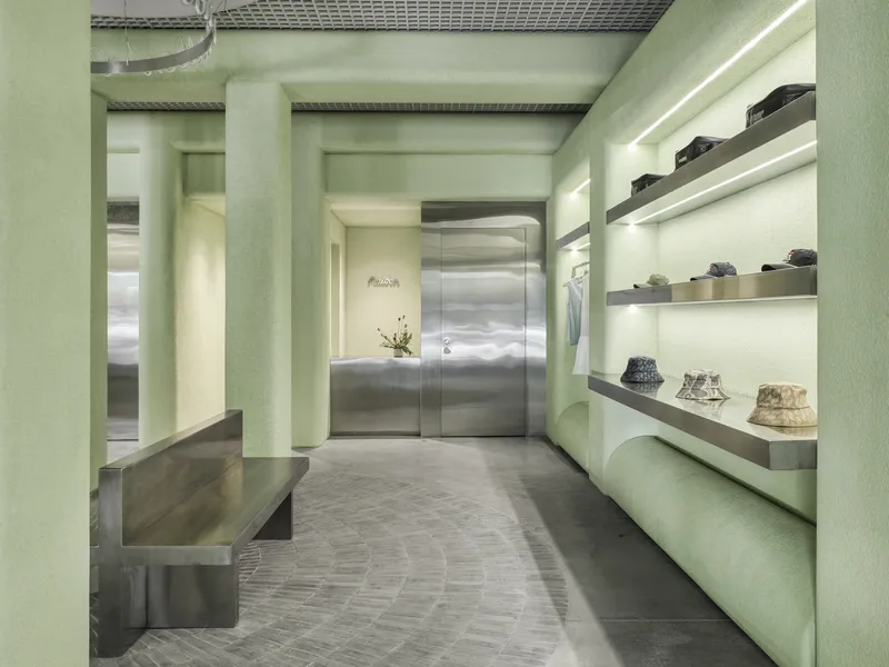 Retail interior with pale green columns, backlit display shelves, and polished concrete herringbone floor