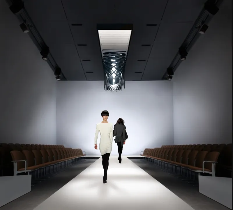 Gallery interior with models walking the illuminated runway beneath a suspended lattice light fixture