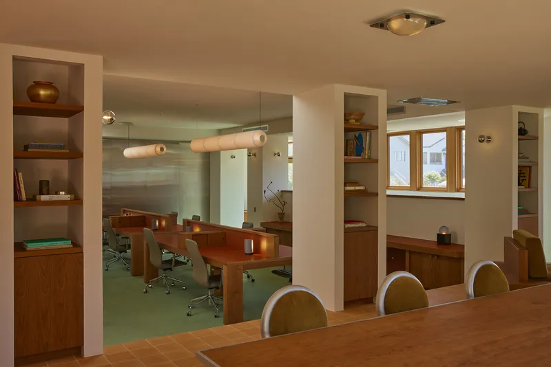 View through built-in walnut shelving toward the conference table and green carpet beyond