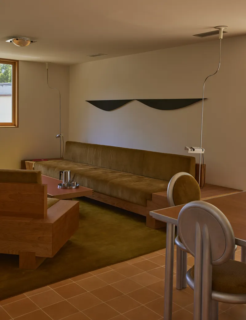 Banquette seating along platform with olive carpet and terracotta tile floor in daylight