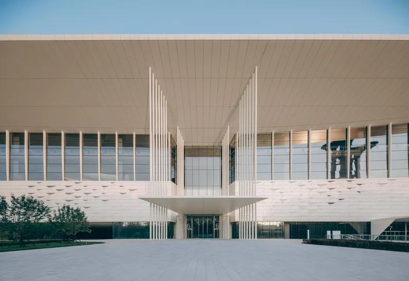 Frontal view of the entrance with vertical white fins under a blue clear sky