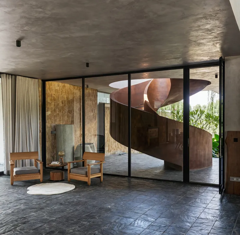 Interior view through glazed doors to corten steel spiral staircase in planted courtyard