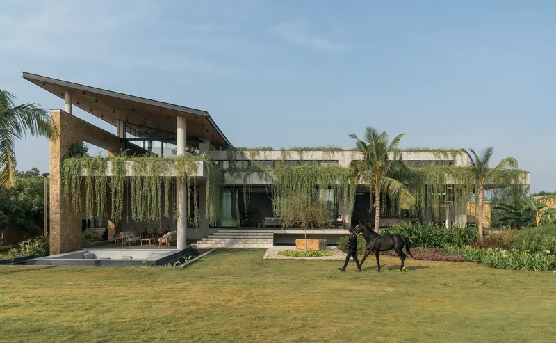 Front elevation with cascading greenery from roof planters and rider on horse crossing lawn