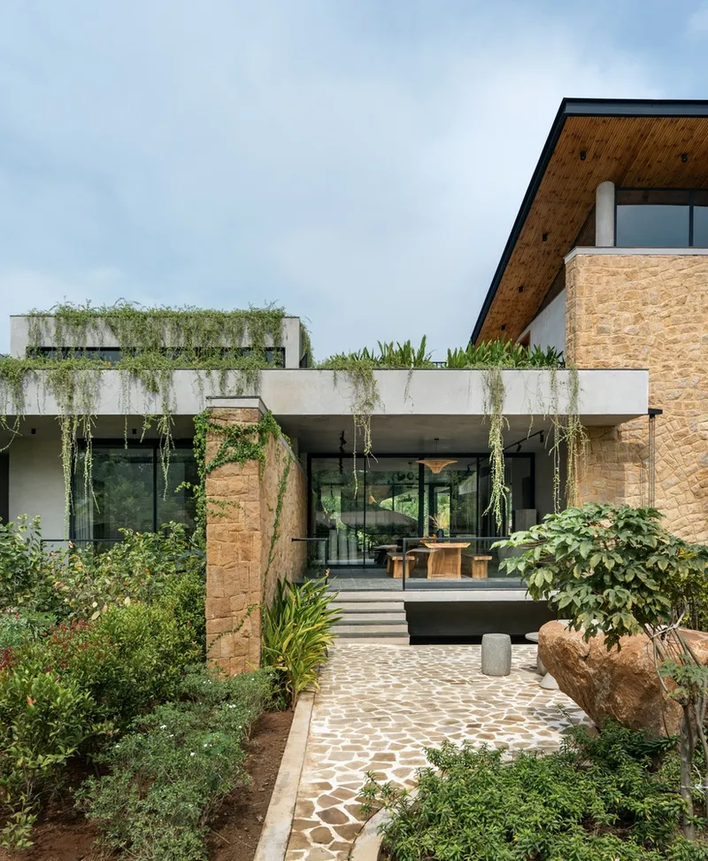 Entry path with stone pavers winding through planted beds toward cantilevered concrete volume
