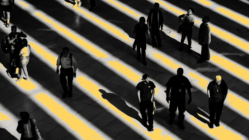 Overhead view of pedestrians crossing paving with alternating light and shadow stripes from sunlight