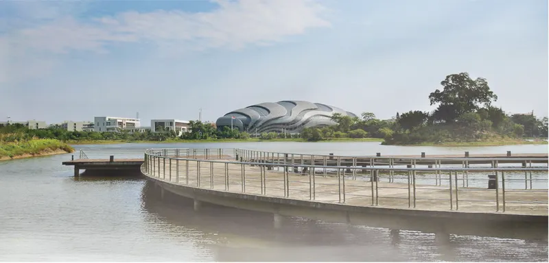 Timber floating boardwalk extending toward the curved roof structure across the river under afternoon light