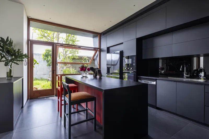 Kitchen with dark cabinetry and island looking through timber-framed glazed doors to the garden