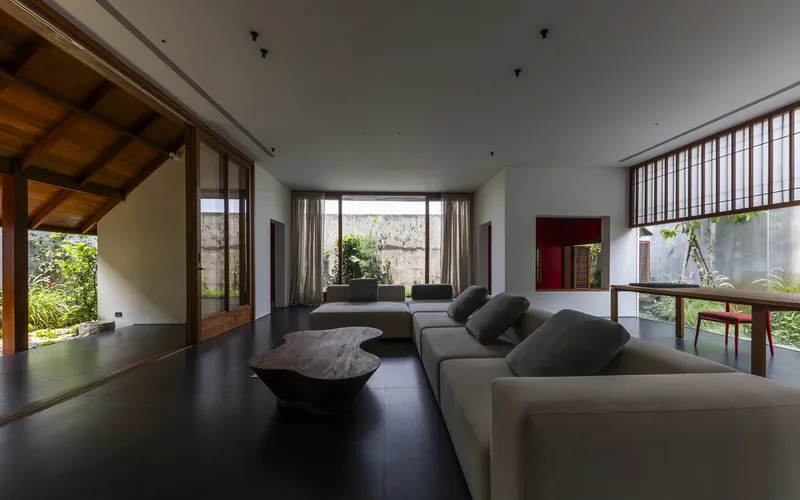 Living room with sectional sofa and slatted screen opening to multiple courtyard gardens in daylight