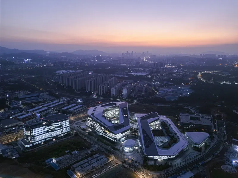 Aerial view of the illuminated campus at dusk with distant mountains on the horizon