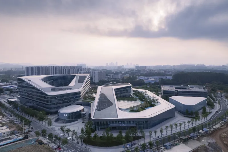 Aerial view of two triangular office buildings with white curved roofs under overcast skies