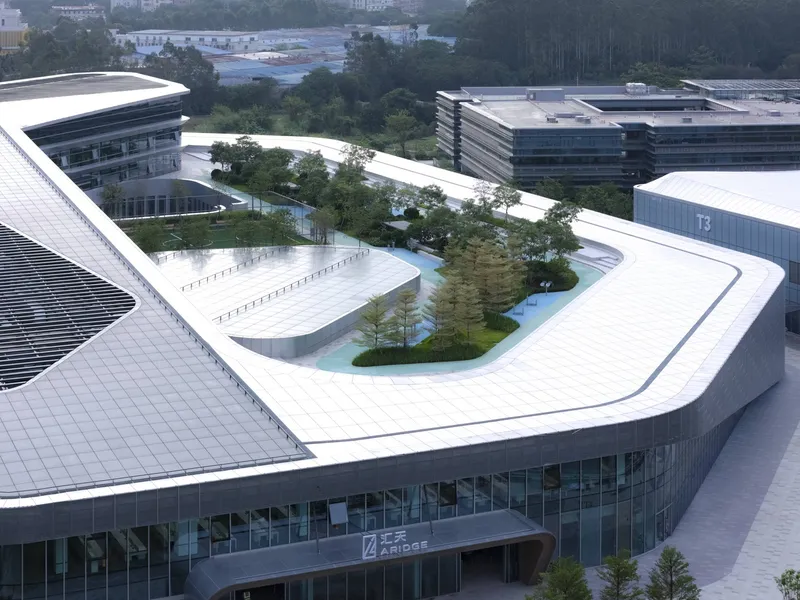 Rooftop garden with planted beds and trees set within the white parapets of a triangular building