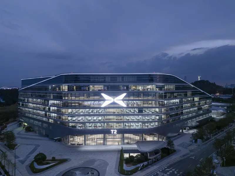 Night view of the glass facade with horizontal louvers and illuminated office floors at twilight