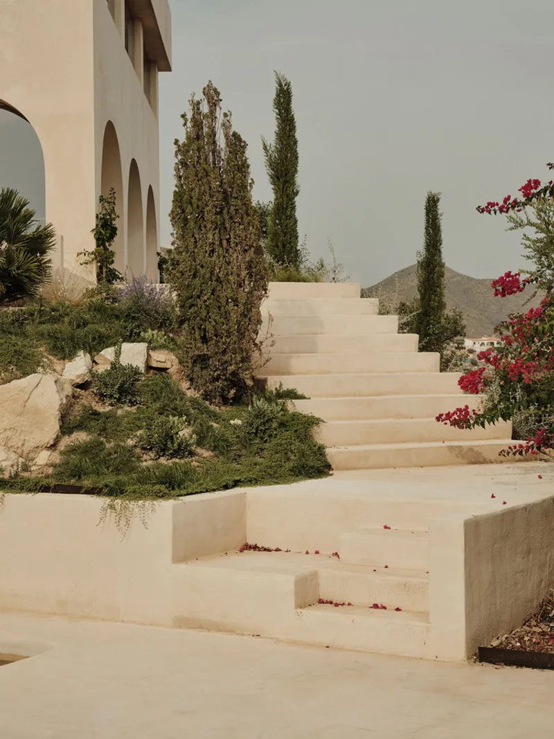 Stone staircase threading through planted beds of cypress and bougainvillea with distant mountain views