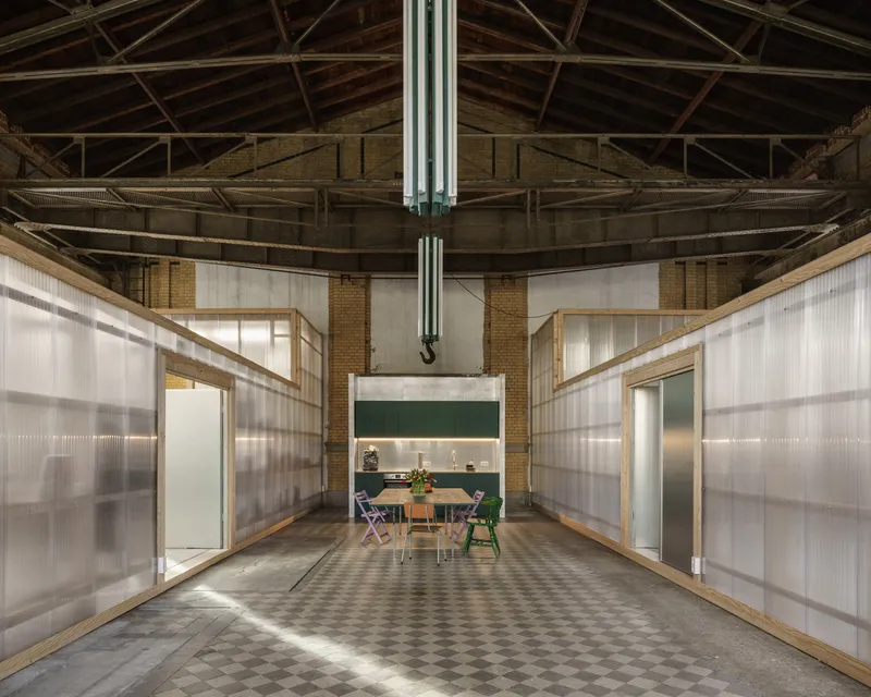 Interior workspace with translucent polycarbonate partitions and exposed timber truss roof under central pendant light