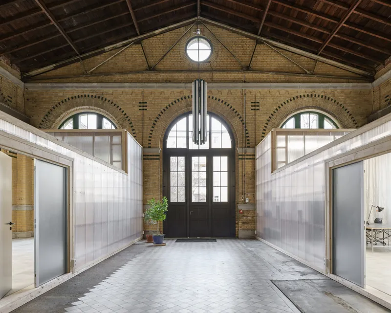 Arched brick facade with three tall windows and round oculus above central black steel entrance doors