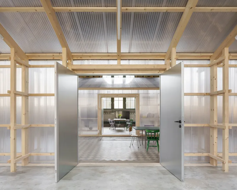 Open double door framing view into dining area with table and chairs beneath timber truss ceiling
