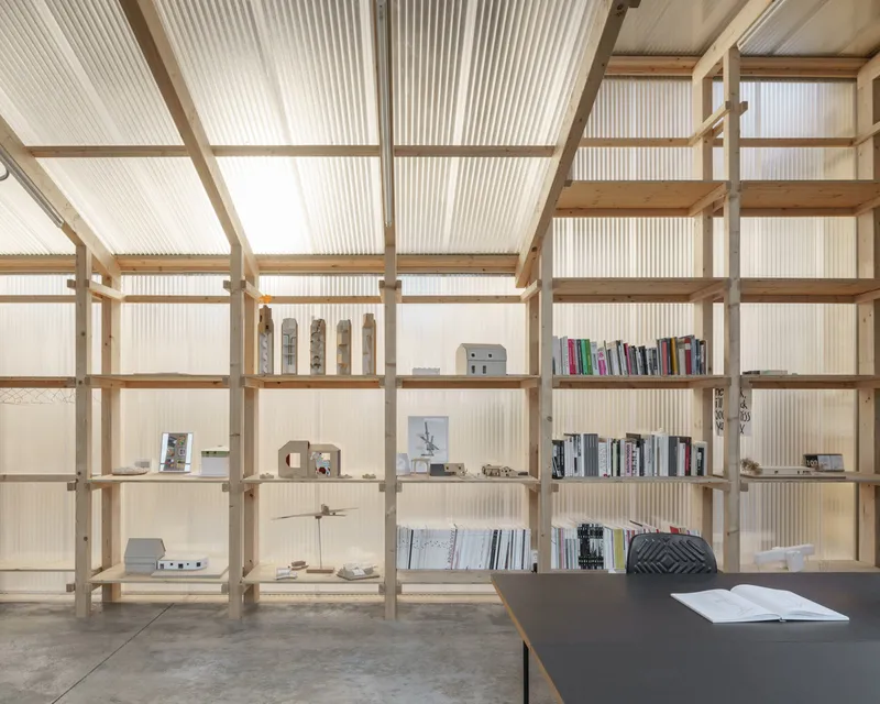 Timber frame shelving unit against translucent corrugated wall panels with natural light filtering through