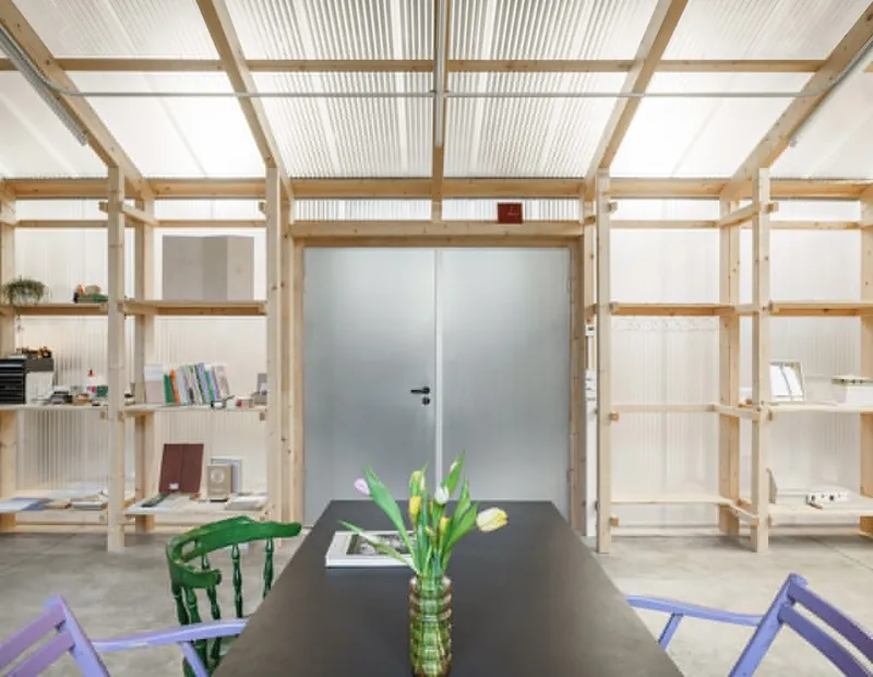 View through timber frame shelving toward frosted glass double doors with tulips on table