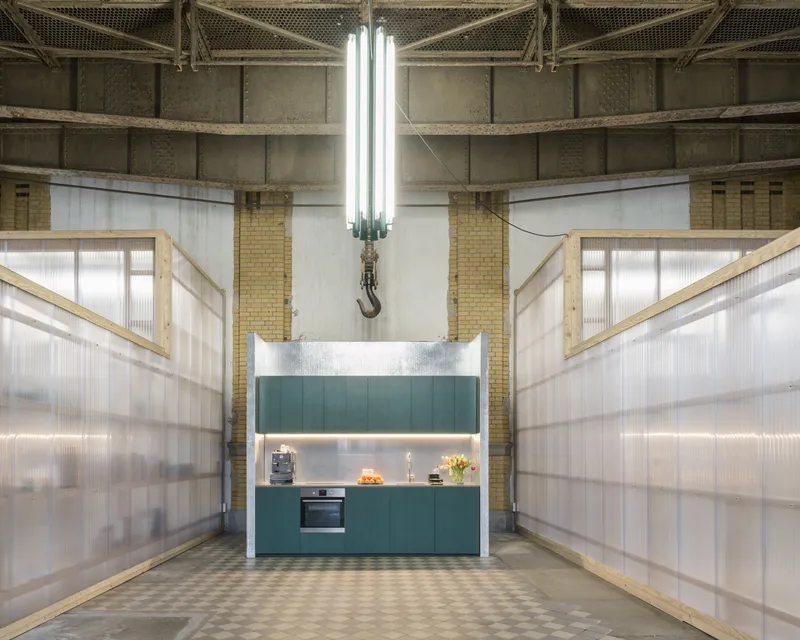 Kitchen unit with teal cabinetry suspended under industrial pendant fixture with hook and chain