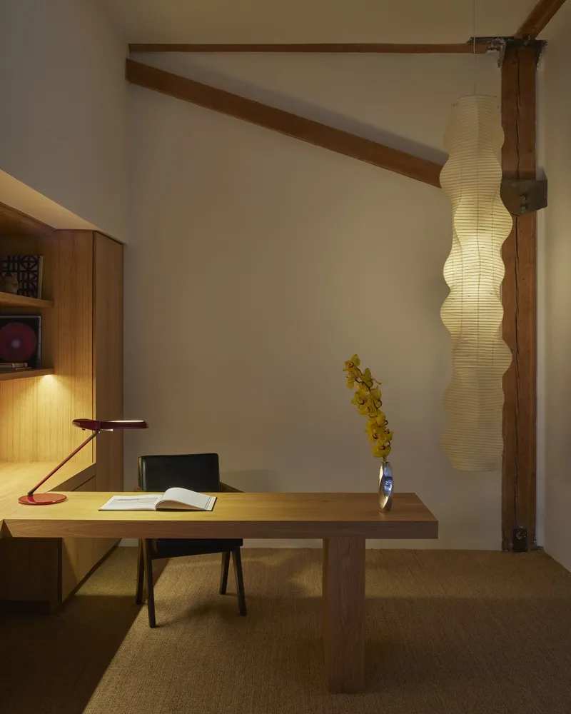 Private office with timber desk, task lamp, column pendant fixture, and exposed beams beneath white walls