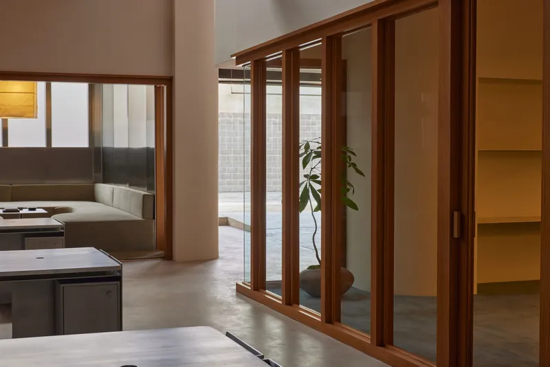 Timber-framed sliding glass doors opening from the polished concrete floor to a courtyard with a potted plant