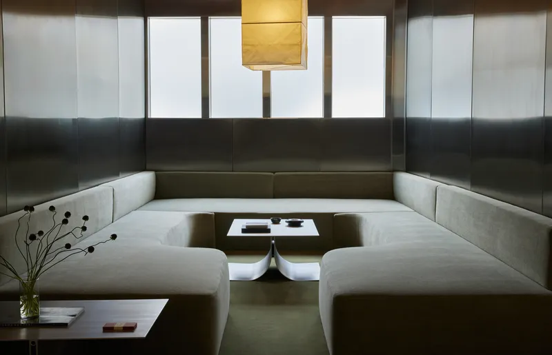 Sunken seating pit with continuous upholstered benches, low table, and translucent clerestory windows above blackened steel