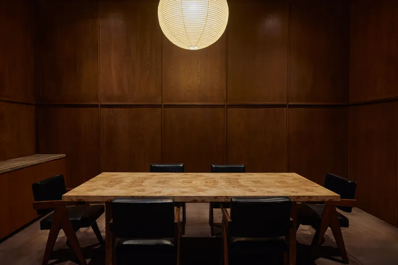 Conference room with wood-paneled walls, paper sphere pendant and light oak table surrounded by dark chairs
