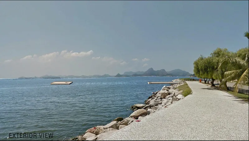 Stone riprap shoreline with paved path and palm trees along the waterfront