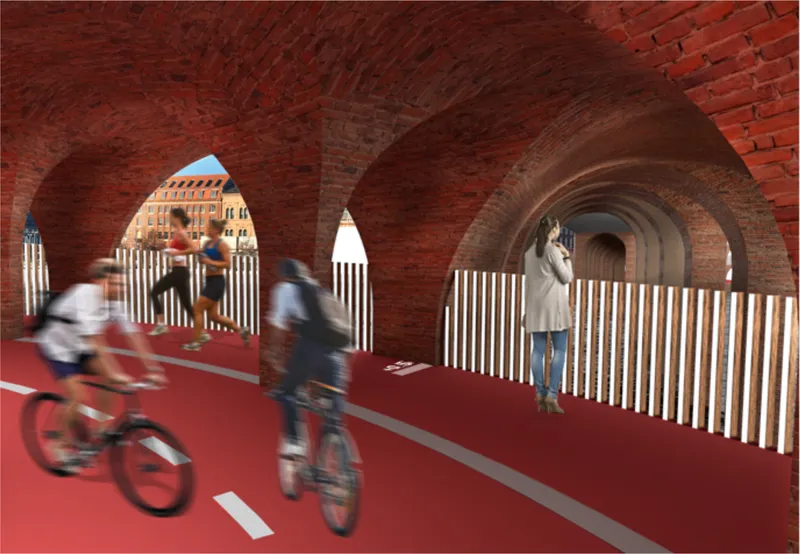 Interior of the vaulted brick passage with cyclists riding past timber railings and arched openings to the canal